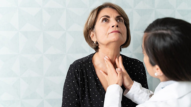 doctor performing thyroid exam on woman