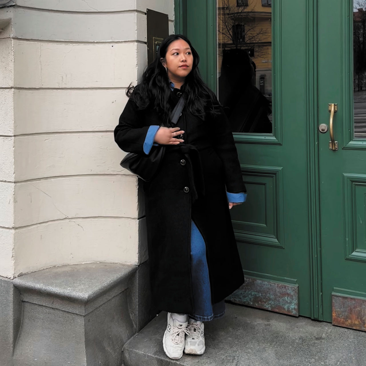 The writer in a black coat in front of a green door