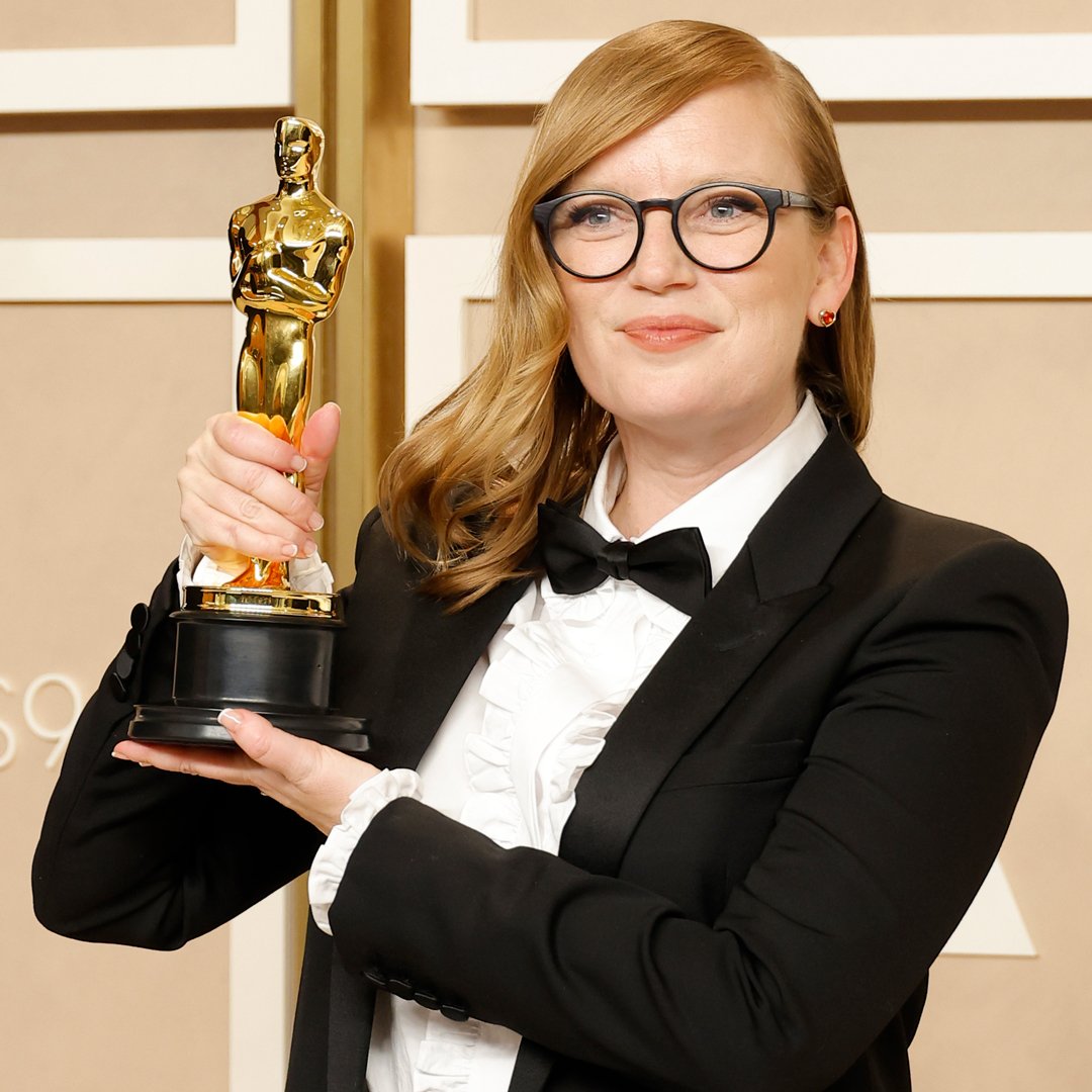 A photo of a woman in a tuxedo holding an Oscars statuette