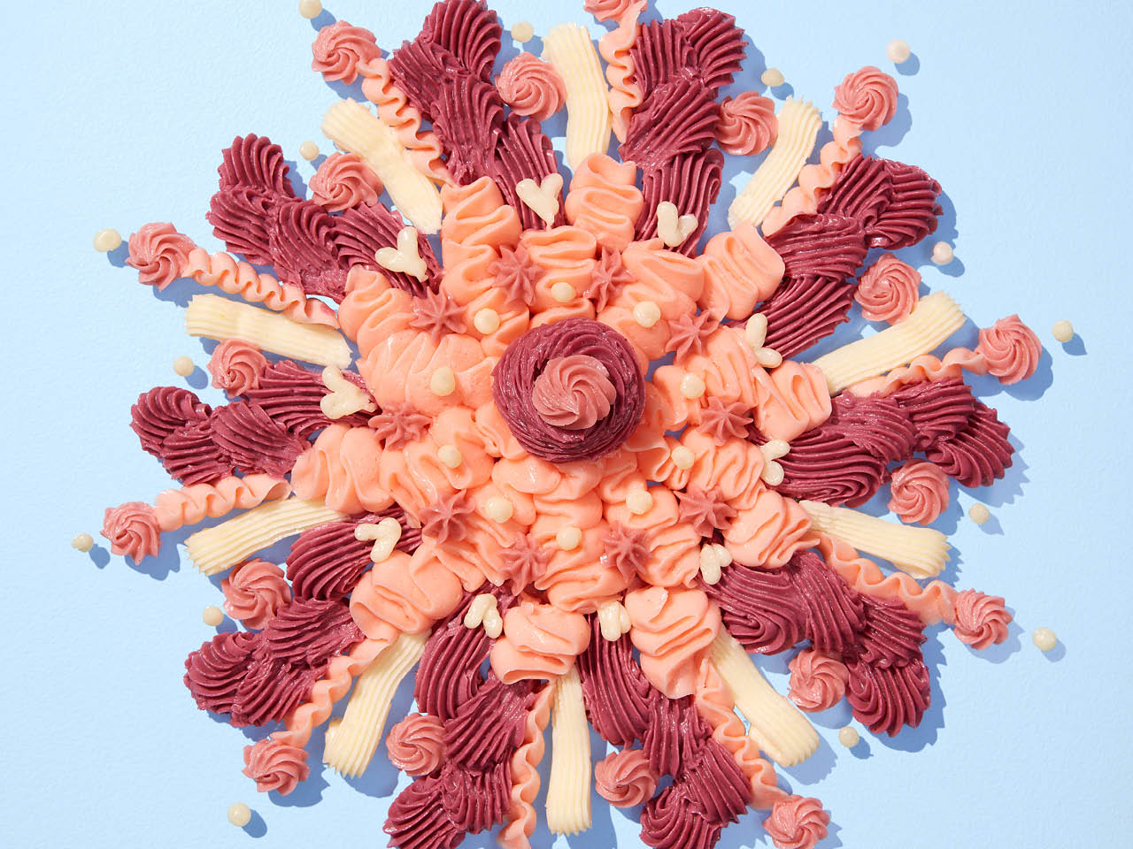 A flower design of pink, white and red icing on a baby blue background
