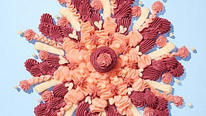 A flower design of pink, white and red icing on a baby blue background