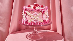 A lemon poppy seed layer cake decorated with pink and white buttercream icing