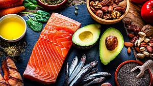 Salmon, avocados, sardines and other healthy foods laid out on a black background