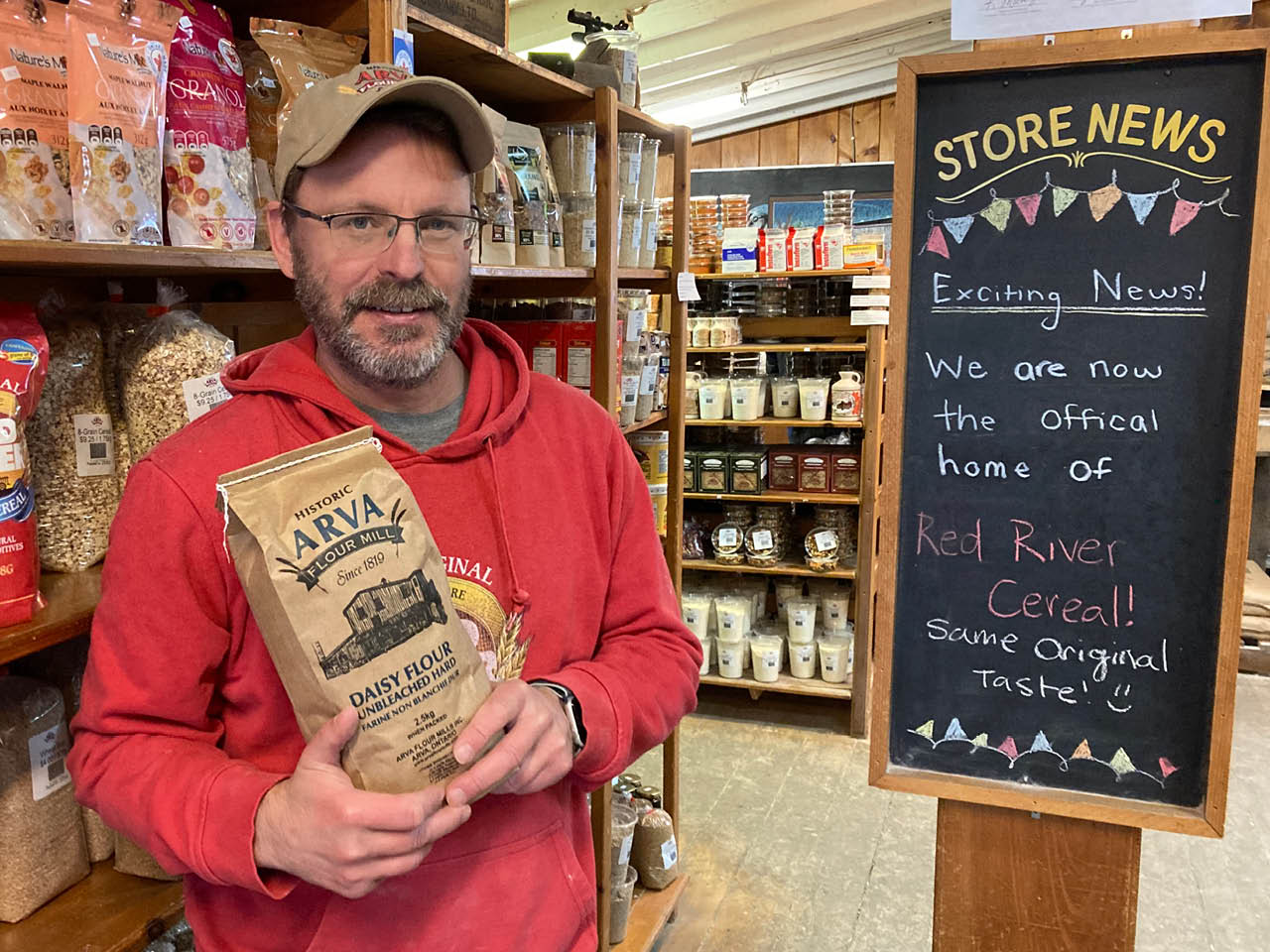 A photo of a man holding a bag of flour in a general store.