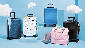 Five of the best carry-on suitcases tested by Chatelaine, seen on a blue set with clouds.