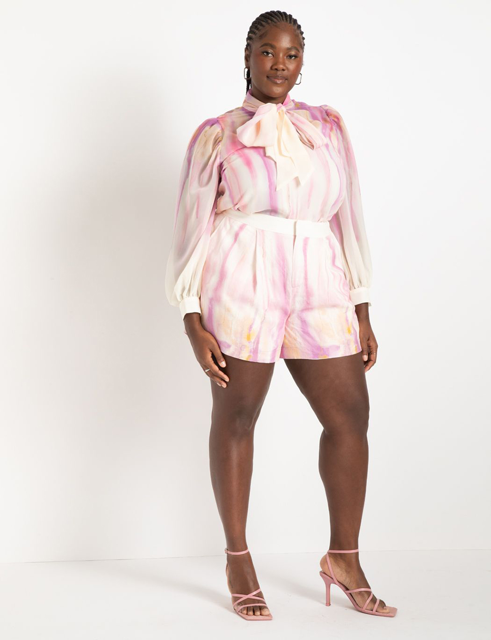A model wearing tie-dye pink and cream shorts from Eloquii.
