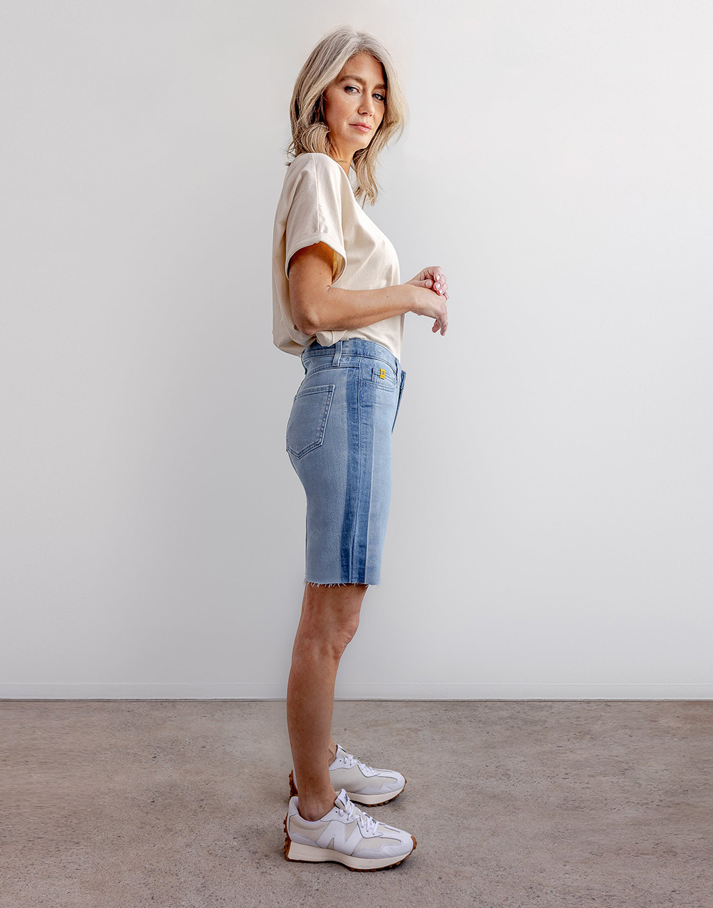 A model seen from the side wearing long denim shorts in two-tone denim from Yoga Jeans.