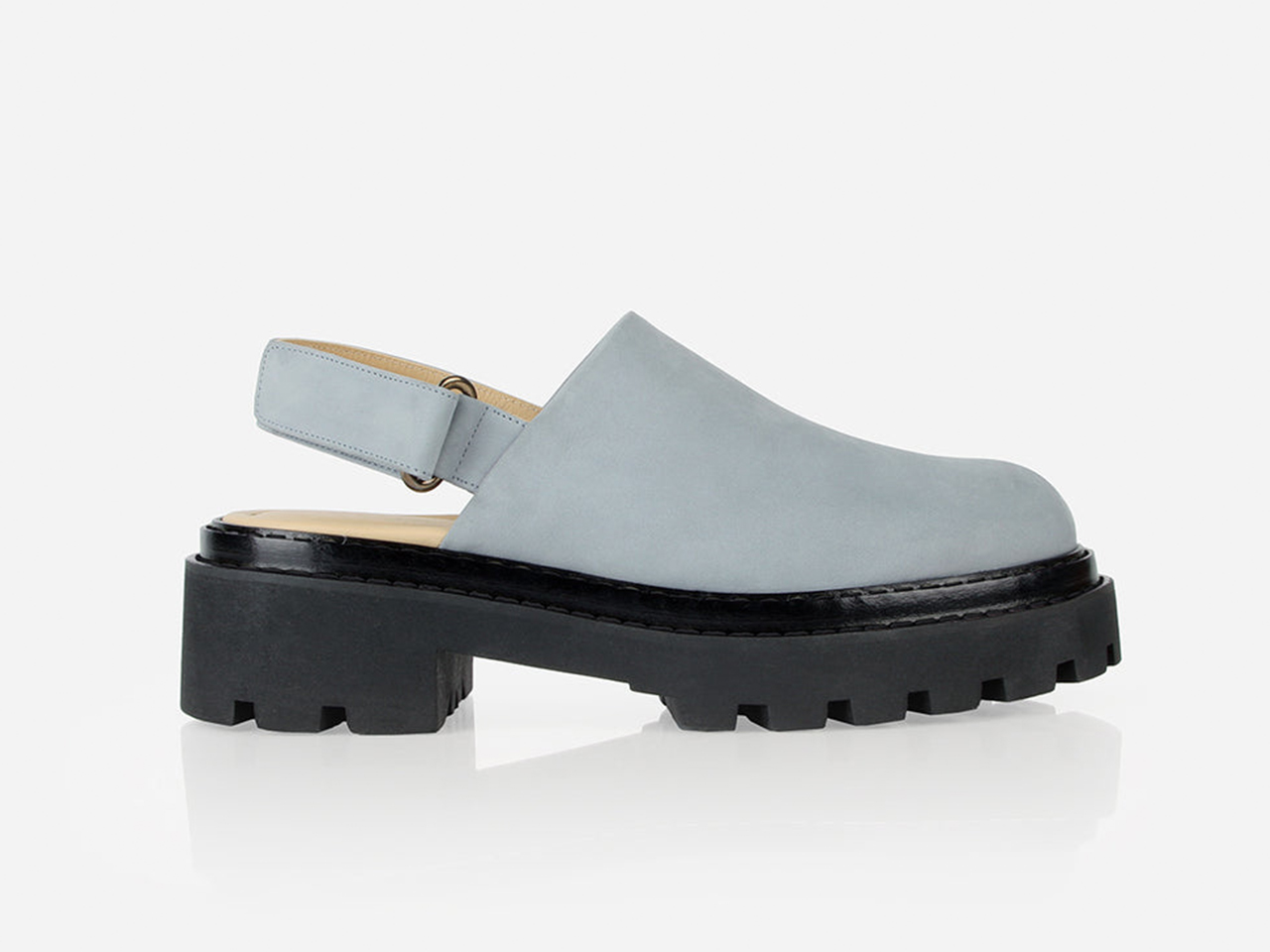 A side profile of a pair of pastel blue suede clogs with black lug soles from Poppy Barley.