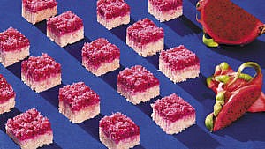 Squares of dragon fruit grater cake arranged in rows beside sliced dragon fruit