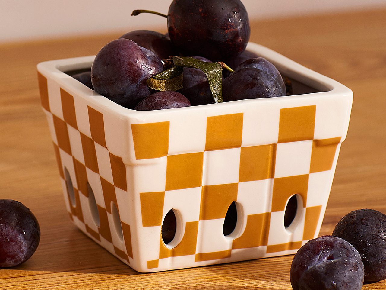 A ceramic checkered fruit bowl with drainage holes.