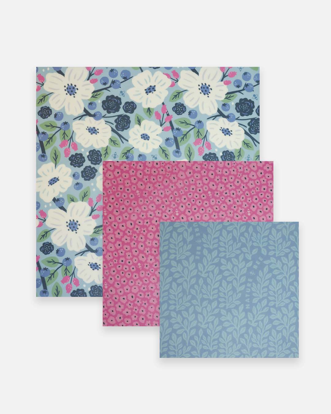 Three nature bee beeswax wraps, one floral patterned, the other pink and blue, on a white background