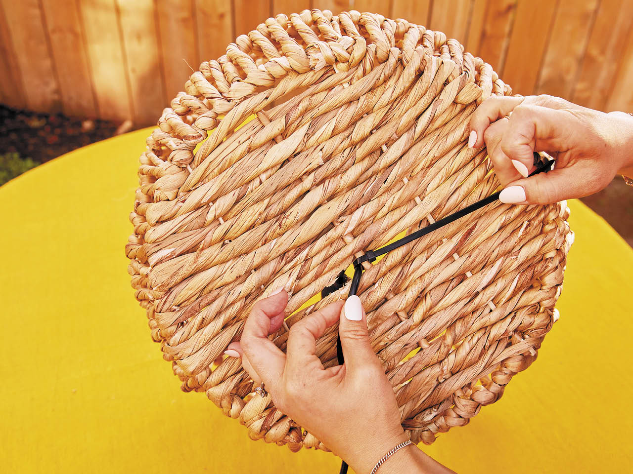 A wicker basket being transformed into a lampshade for a solar-powered outdoor pendant light.