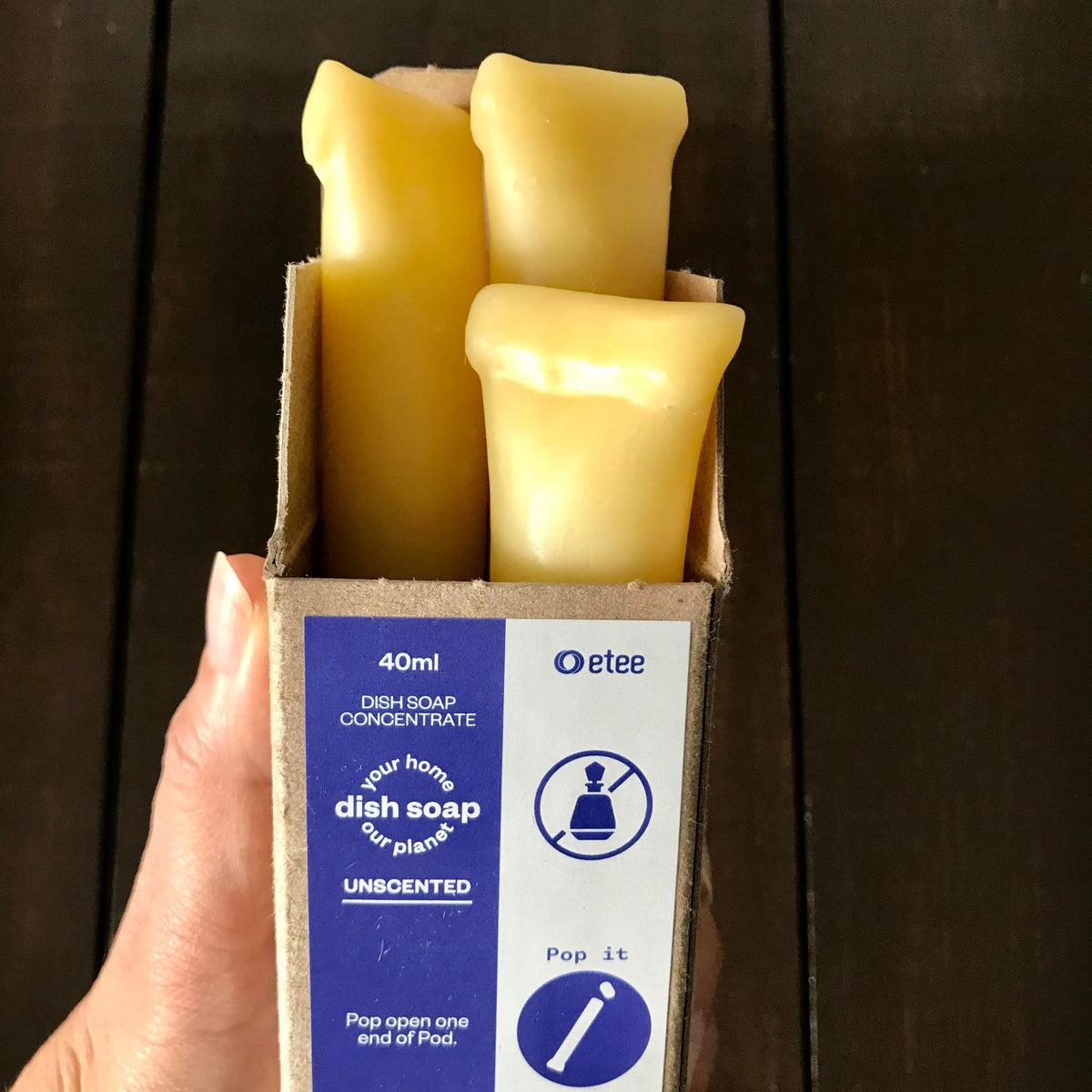 A hand holding a box of Etee concentrated dish soaps, packaged in beeswax