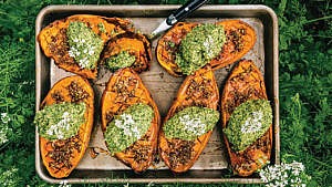 a baking tray of sweet potatoes with a filling of pesto and nuts