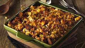 A green casserole dish filled with stuffing.