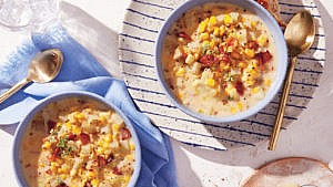 A bowl of corn chowder with bacon soup seasoned with fresh pepper.