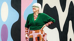 Vancouver entrepreneur Anna Heyd wearing a maximalist style outfit including a patterned skirt and green cardigan, photographed against a murale.