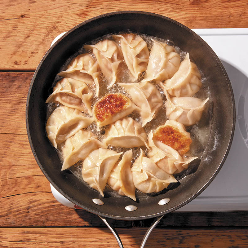 Posticker method: Jiaozi (Chinese dumplings) being cooked in a single layer on a frying pan