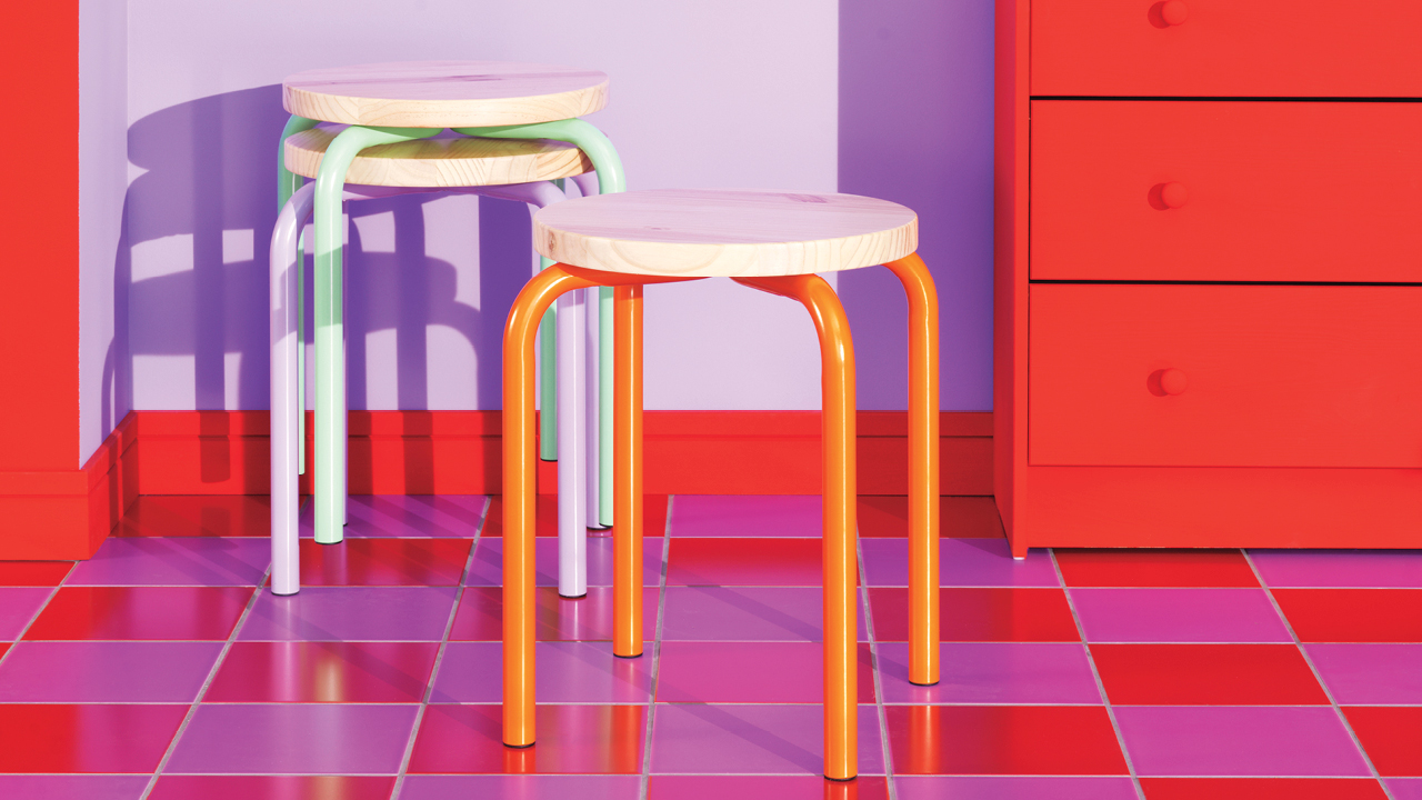 Three colourful Ikea stools on red and purple checkered tiles.