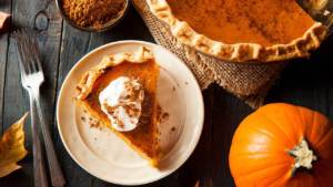 close-up photo of a slice of pumpkin pie on a white plate.