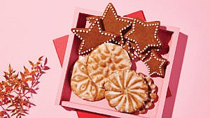 Star-shaped gingerbread cookies arranged in a pink box with iced biscuits