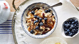 slow cooker fruit and nut steel-cut oats with fresh blueberries and honey on a white ceramic bowl