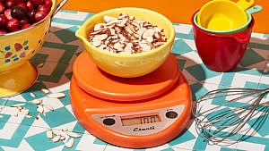 A yellow bowl full of almonds on an orange Eskali kitchen scale: How to measure baking ingredients
