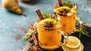 two cups of hot toddy garnished with cloves, lemon and cinnamon.