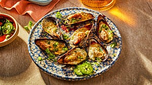 Cheesy jalapeno mussel poppers arranged on a blue speckled plate
