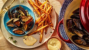 Classic French steamed mussels in a Dutch oven and served on a plate with oven frites and dip
