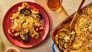 Rice, potato and mussel casserole scooped from a serving tray onto a red plate